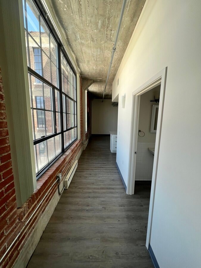 A long hallway with brick walls and windows on the side.
