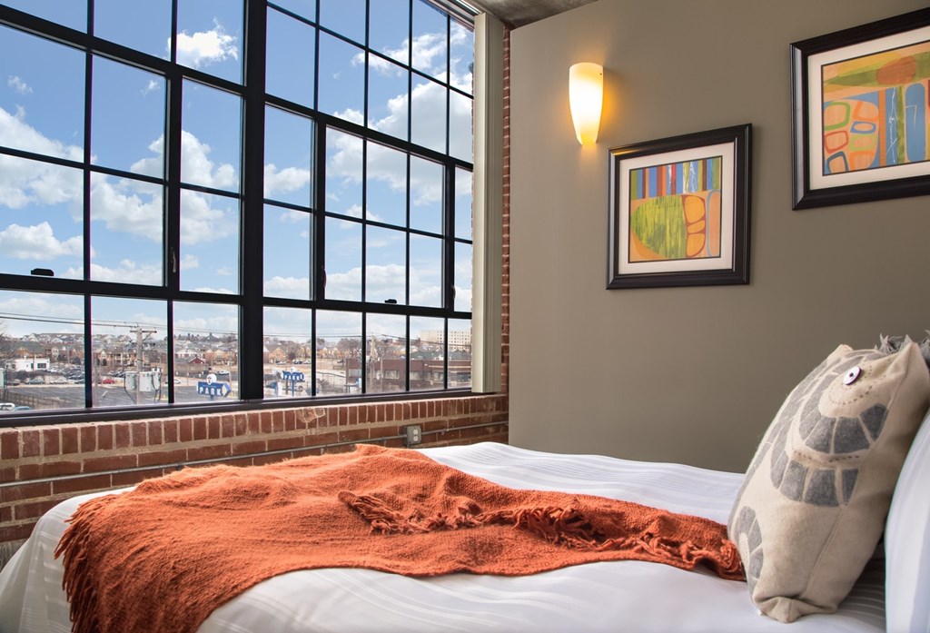 A bedroom with a large window overlooking a cityscape.
