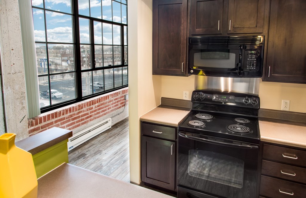A kitchen with a black stove top oven and a black microwave above it.