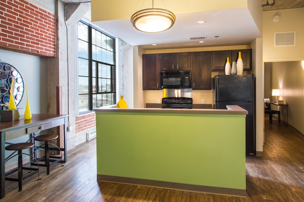 A kitchen with a green counter and a brick wall.