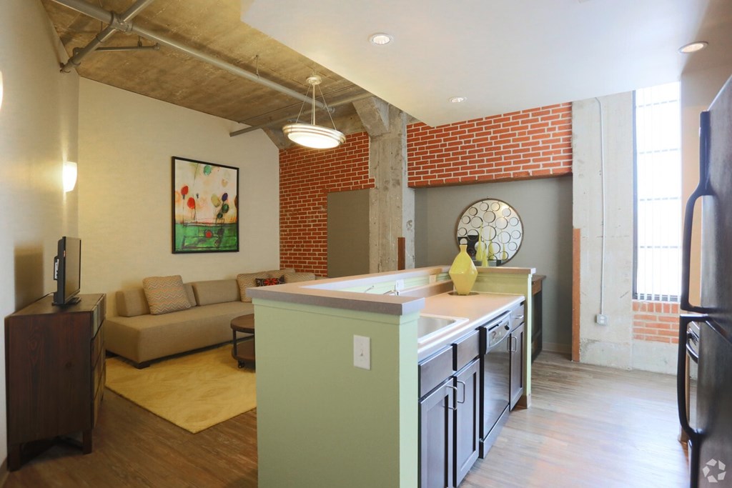 A kitchen with a green island and a couch in the living room.