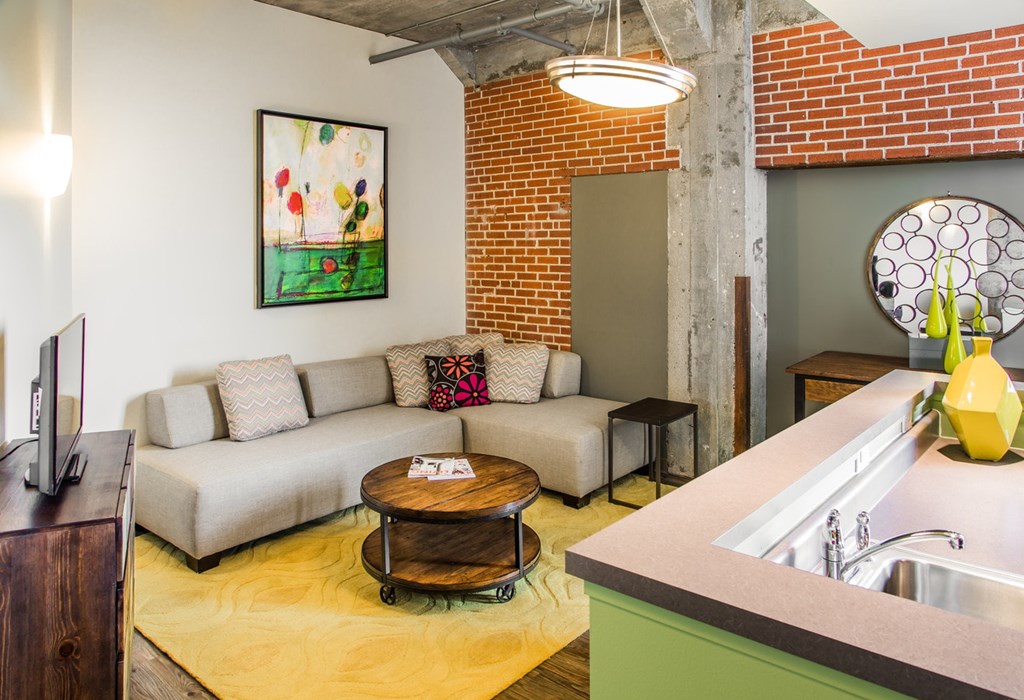 A living room with a couch, a coffee table, and a painting on the wall.