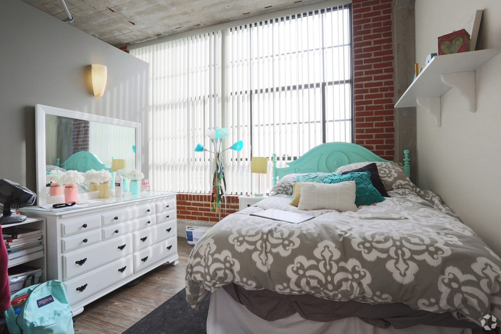 A bedroom with a bed, dresser, and window.