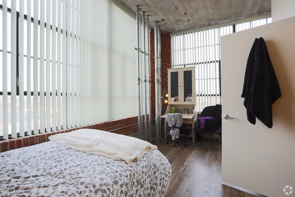 A bedroom with a bed, a chair, and a coat hanging on the wall.