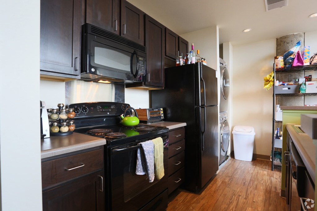 A kitchen with black appliances and wooden floors.
