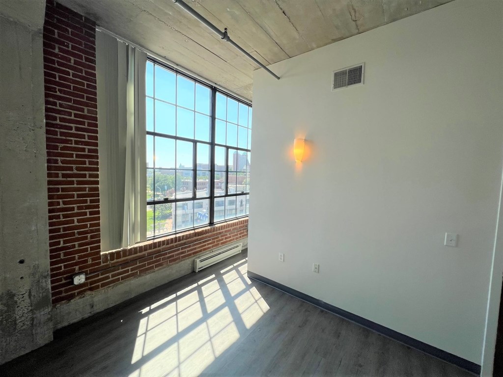 A room with a large window and a brick wall.
