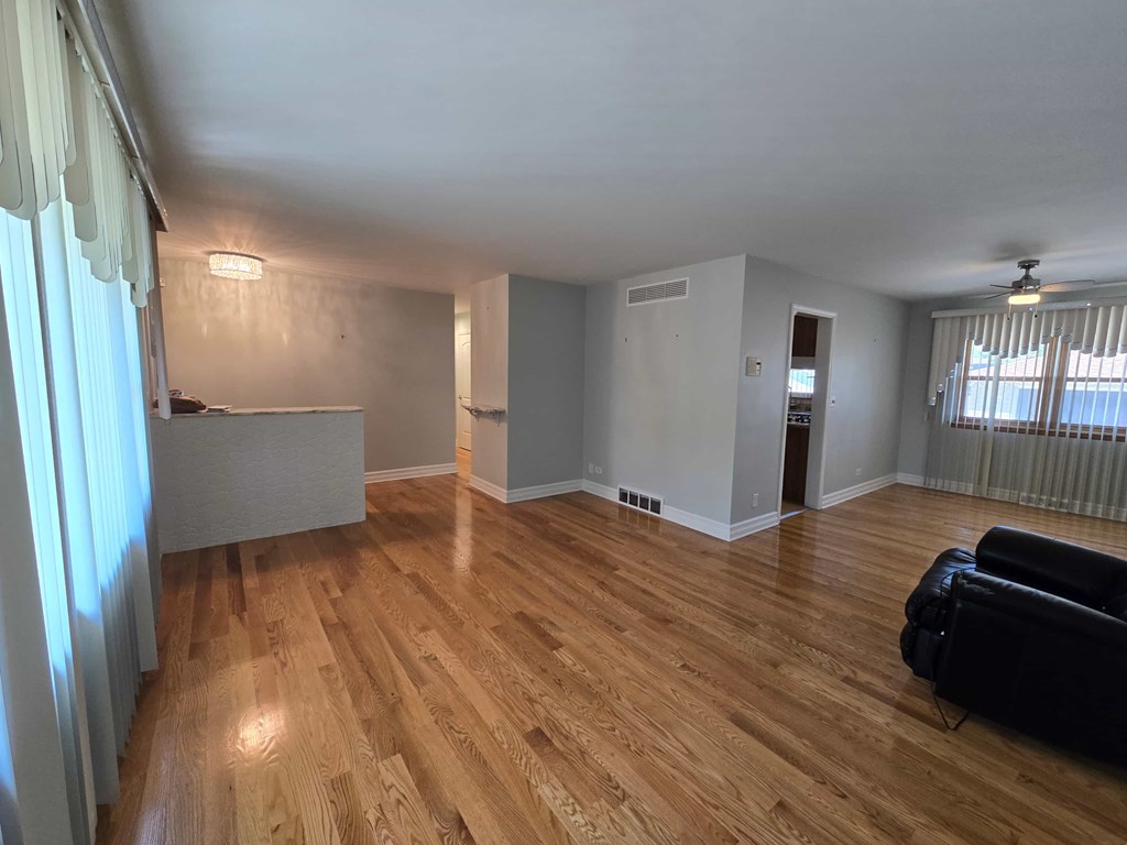 A living room with a black couch and wooden floors.