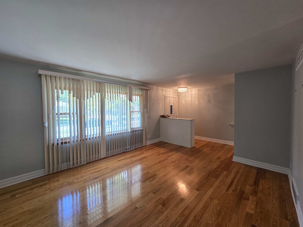 A room with wooden floors and a window with blinds.