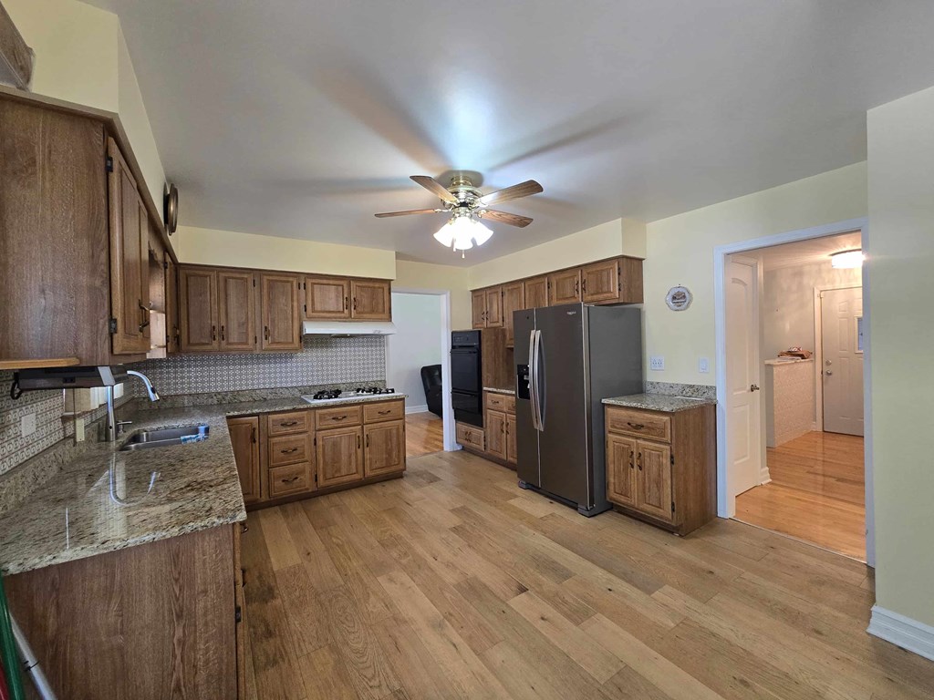 A kitchen with wooden cabinets and a black refrigerator.