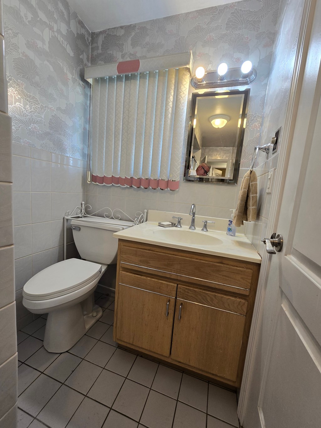 A bathroom with a toilet, sink, and mirror.
