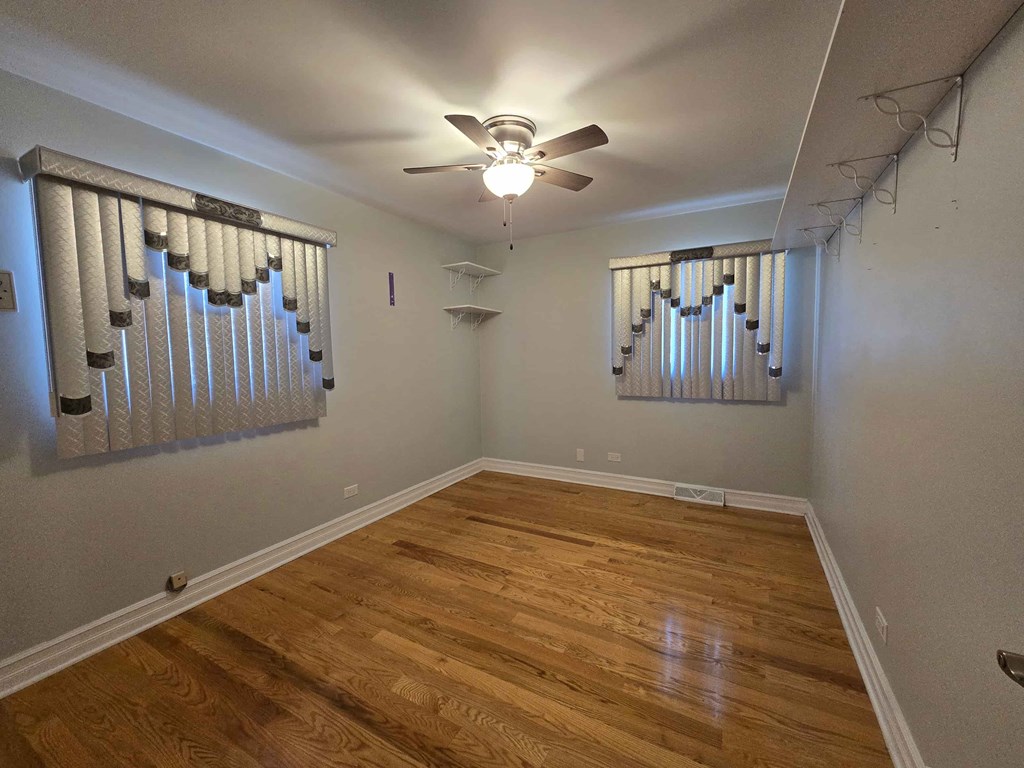 A room with wooden floors and a ceiling fan.