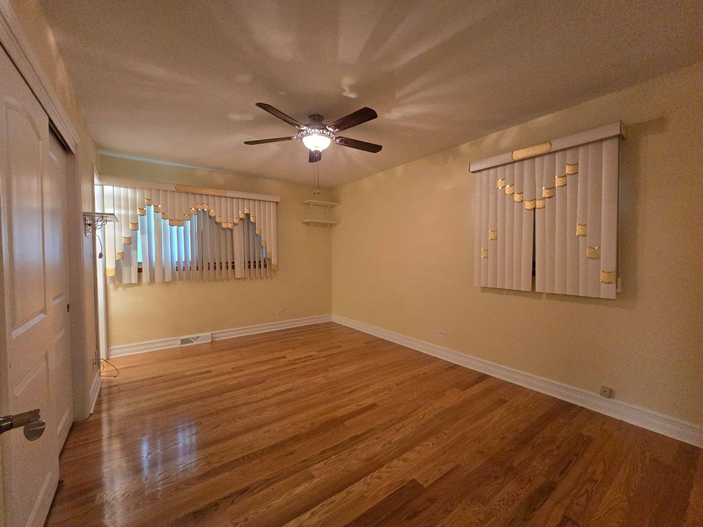 A room with a ceiling fan and wooden flooring.