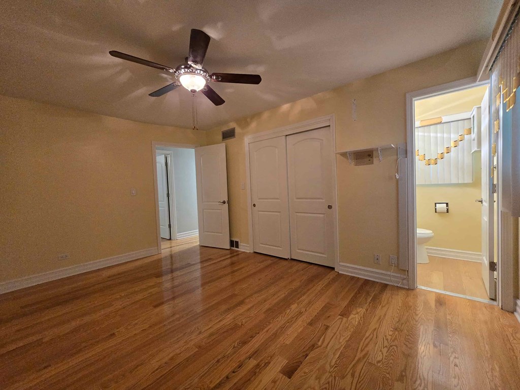 A room with a ceiling fan and wooden floors.