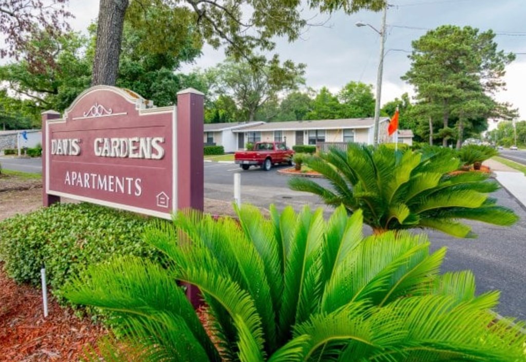 A sign for Davis Gardens Apartments is in front of a building.