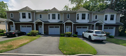 A two-story house with a white car parked in front.