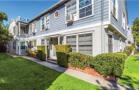 A row of houses with green lawns in front.
