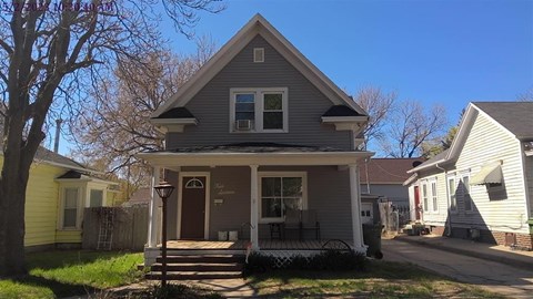 A house with a porch and a tree in front.