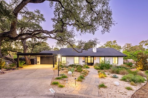 A house with a driveway and a tree in front of it.