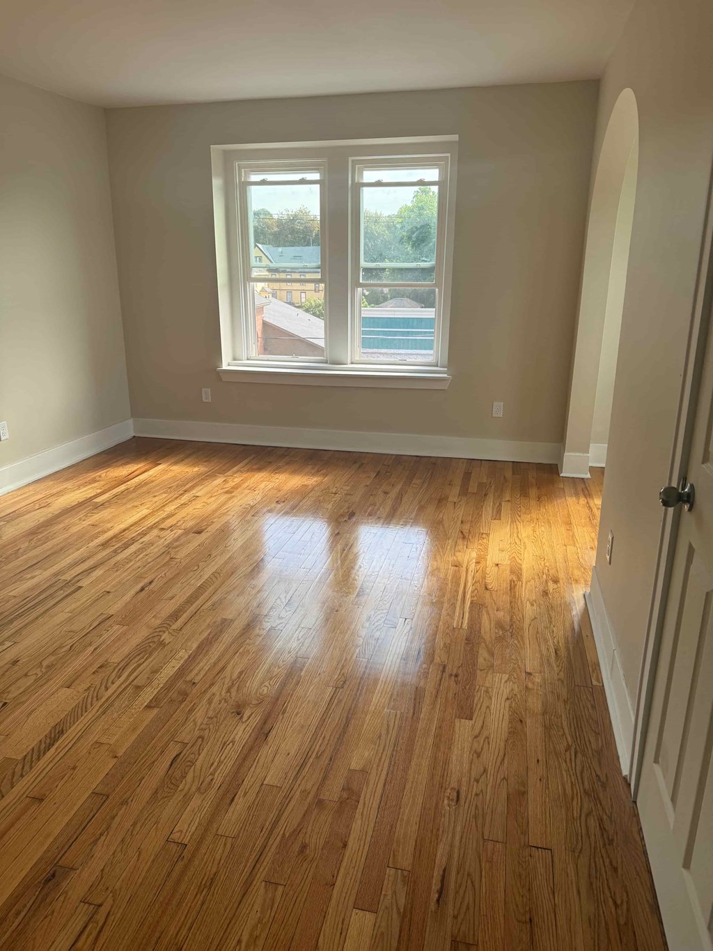 A room with wooden flooring and a window overlooking a pool.