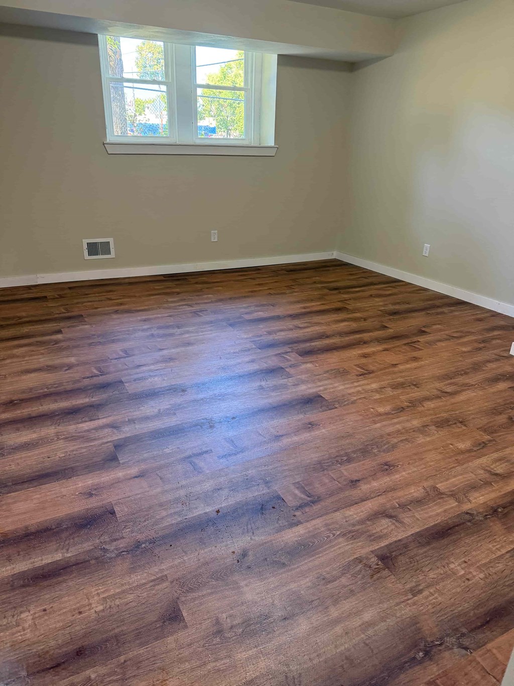 A room with wooden flooring and a window.
