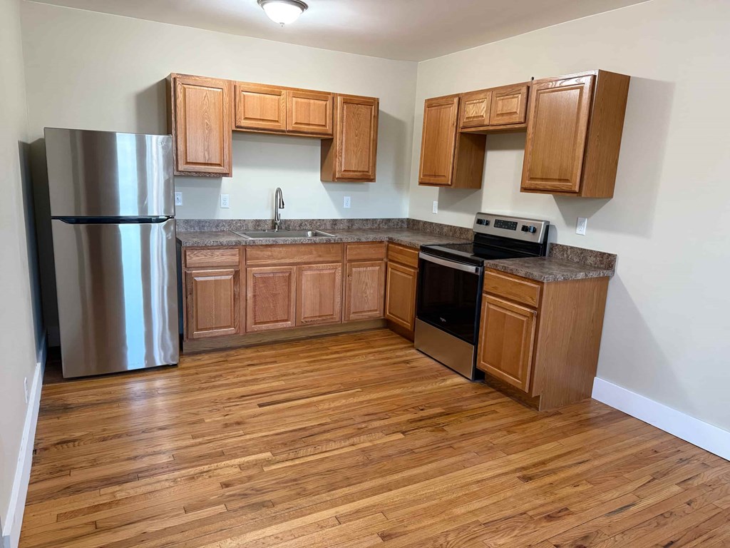 A kitchen with wooden cabinets and a stainless steel refrigerator.