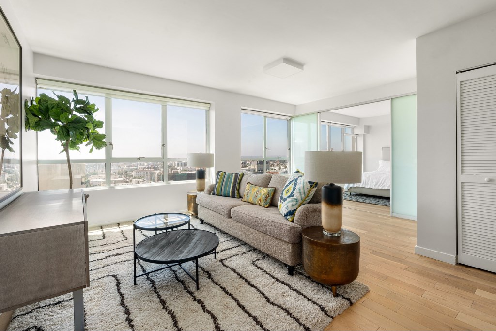 A living room with a couch, coffee table, and a view of the city.
