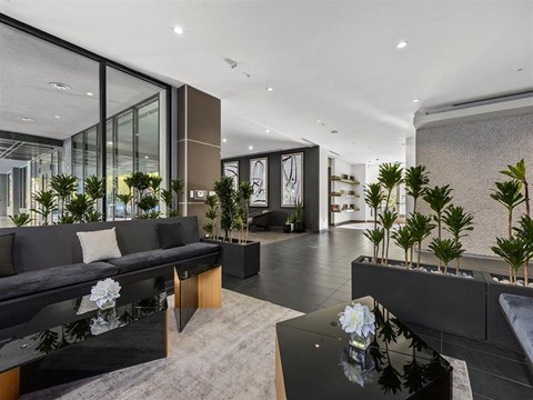 A modern living room with a black sofa and a glass table.