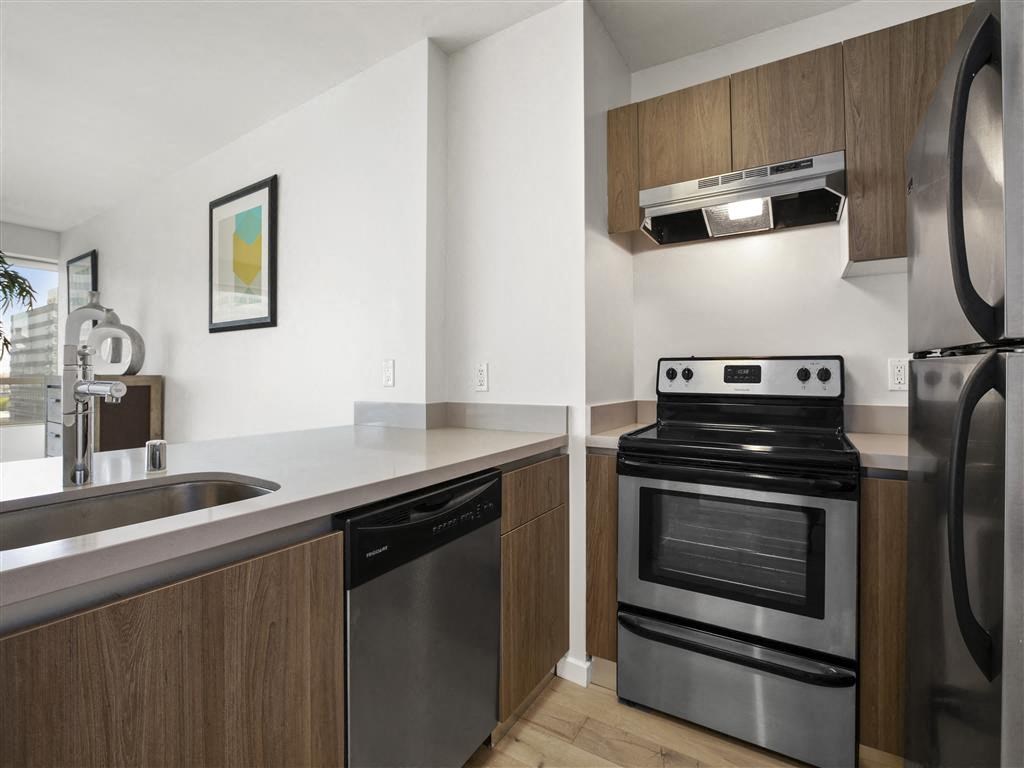 A modern kitchen with a stainless steel refrigerator, dishwasher, and oven.