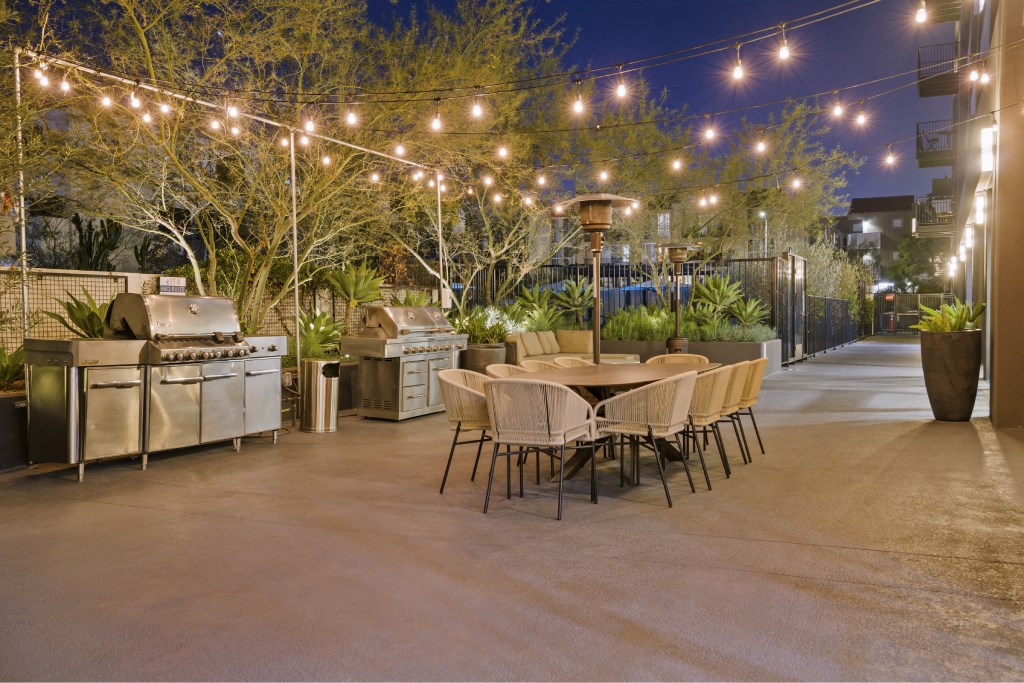 A patio with a table and chairs is illuminated by string lights.