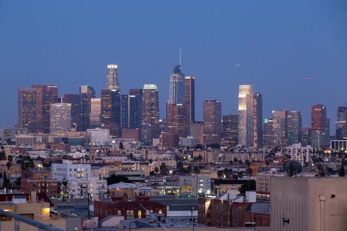 A cityscape at dusk with buildings illuminated against a darkening sky.