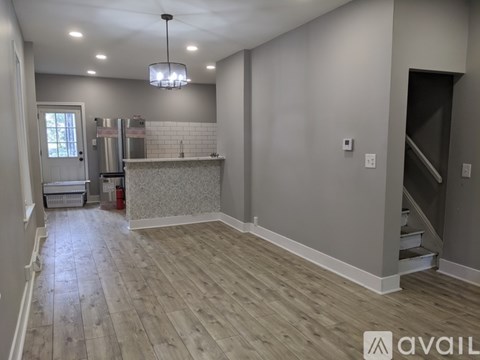 A kitchen area with a refrigerator, a counter, and a staircase.