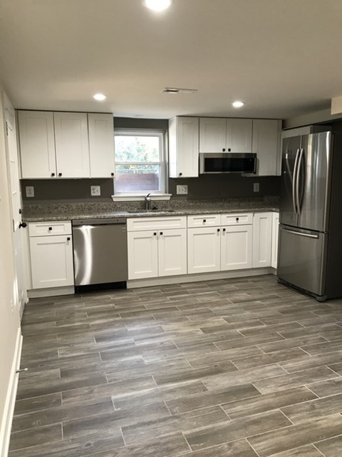A kitchen with white cabinets and a black countertop.