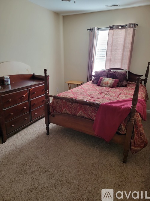 A bedroom with a bed, dresser, and window.