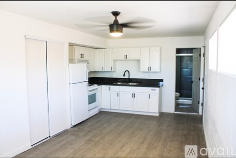 A kitchen with white cabinets and a black countertop.