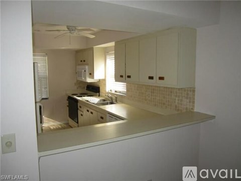 A kitchen with white cabinets and a tiled backsplash.
