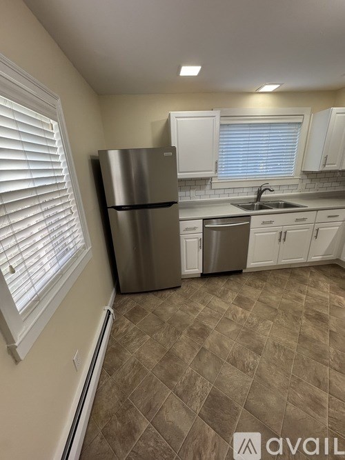 A kitchen with a stainless steel refrigerator and white cabinets.