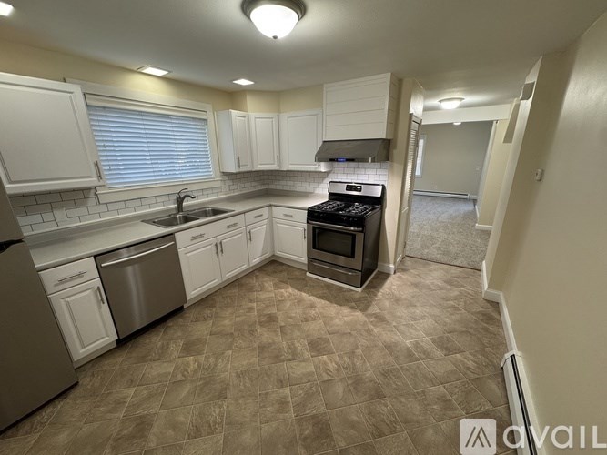 A kitchen with white cabinets and a tiled floor.