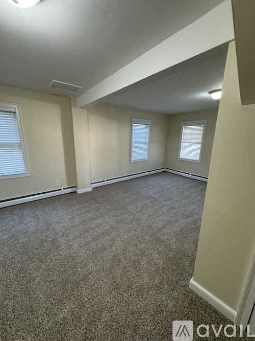 A carpeted room with two windows and a white ceiling.