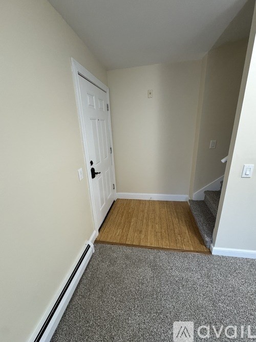 A room with a white door and a grey carpet.