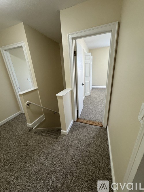 A hallway with a carpeted floor and a doorway leading to another room.