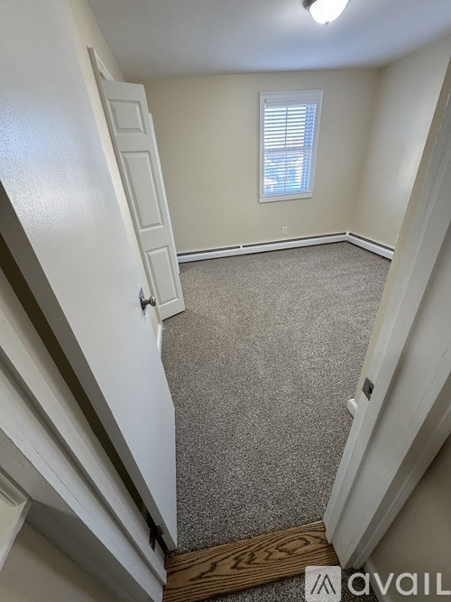 A white door is open to a hallway with a carpeted floor.