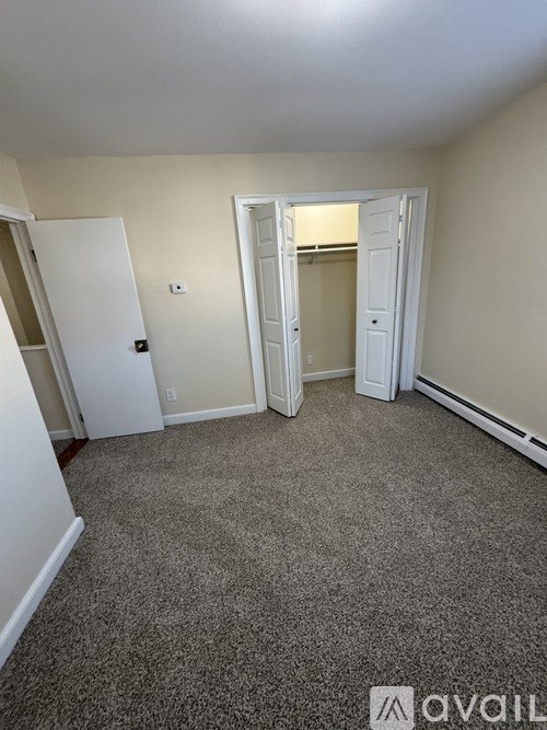 A room with carpeted floor and two doors.