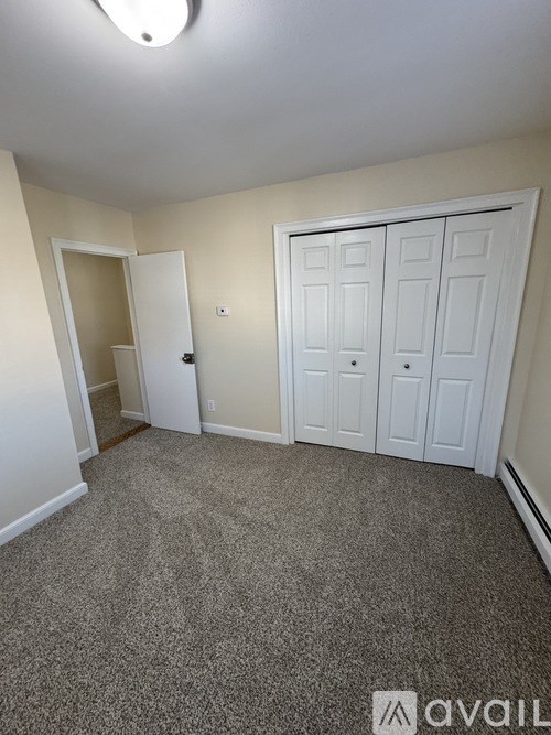 A room with a carpeted floor and a white door.