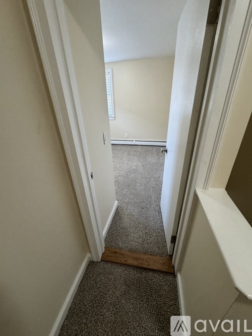 A hallway with a carpeted floor and white walls.