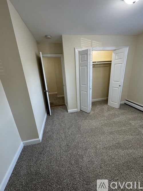 A room with carpeted floor and two open doors.