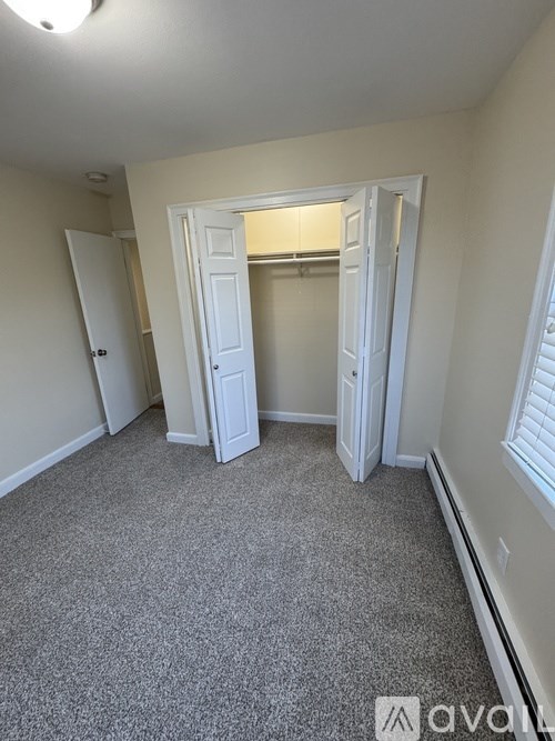 A carpeted room with a doorway leading to another room.