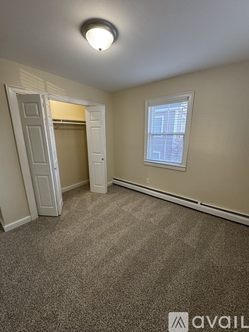 A room with a carpeted floor and a window with blinds.