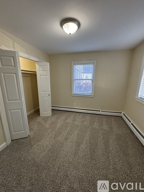 A room with a carpeted floor, a window, and a door.