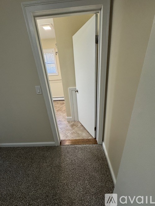 A hallway with a carpeted floor and a door on the right.