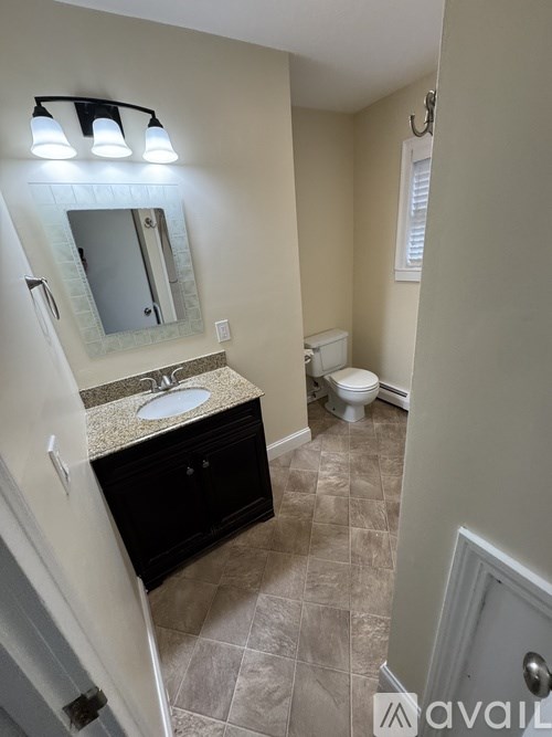 A bathroom with a sink, toilet, and a mirror.